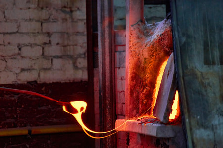 Murano glass-blowing factory. blower forming beautiful piece of glass: put iron rod with attached glass object in furnace to make the glass malleable. Venice, Italyの写真素材