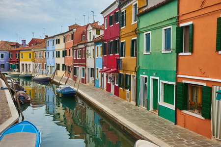 Burano island narrow cobblestone street between colorful houses buildings with multicolored bright walls, blue sky sunny summer day, Venice Province, Veneto Region, Northern Italy. Burano postcardの写真素材