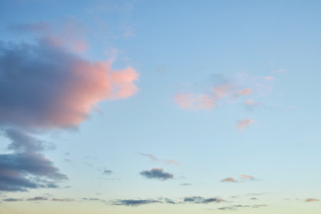 A fragment of a bright sunset sky with bizarrely shaped clouds. Captivating dusk sky displaying a palette of warm hues, perfect for your design projects.の写真素材