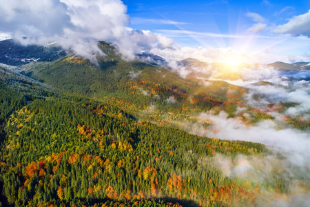 Fog spreads over the mountains at dawn. The sun rises on the horizon. Ukrainian Carpathians in the morning. Aerial drone view.の写真素材