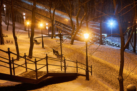 Winter evening in the park, snow-covered benches, bright lights illuminated white snow, New Year's Eve with snow.の写真素材