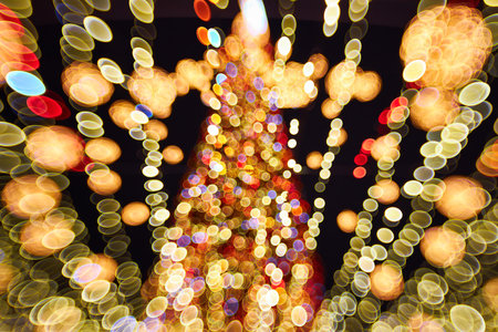 Blurred christmas tree with lights decorations outdoors at night. New Year Celebration.の写真素材