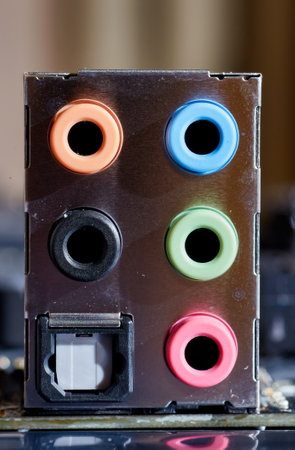 A close-up image of colored audio ports on a computer motherboard, including pink, green, blue, orange, and black ports for various audio inputs and outputs. Perfect for technical or hardware-related visuals.の写真素材