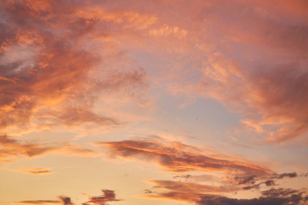 A peaceful sunset sky with vibrant orange, pink, and purple clouds, creating a dramatic evening scene. Perfect for use as a background or backdrop in projects needing natural beauty.の写真素材