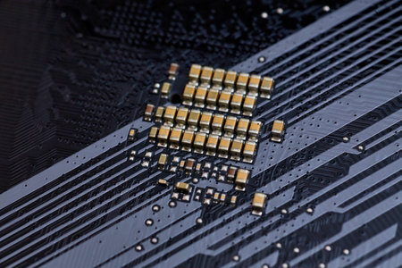A detailed view of surface-mounted capacitors on a motherboard, showing the intricate traces and electronic components. Ideal for illustrating computer hardware, electronics, or technical content related to PC building.の写真素材