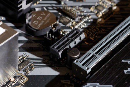 A detailed image of a motherboard showing PCIe slots, capacitors, and various electronic components. Ideal for use in technology-related projects, backgrounds, and technical illustrations.の写真素材