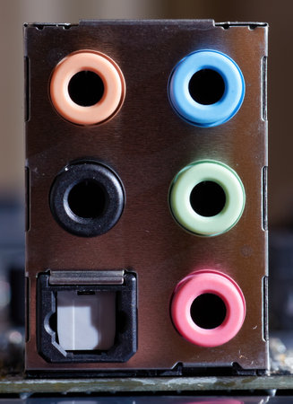 A close-up image of colored audio ports on a computer motherboard, including pink, green, blue, orange, and black ports for various audio inputs and outputs. Perfect for technical or hardware-related visuals.の写真素材