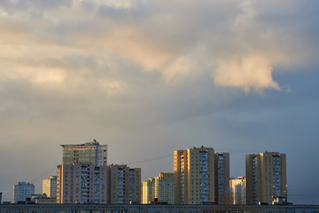 A vibrant sunset sky with dark clouds and orange highlights contrasts against the city skyline. The moody atmosphere captures the beauty of a changing sky over an urban landscape.の写真素材