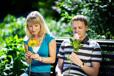 Boy and girl with flowers on a romantic date on a park benchの写真素材