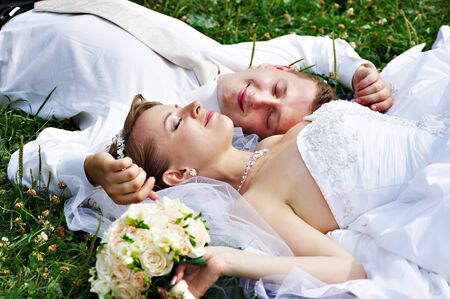 Happy bride and groom at wedding walk on grass in parkの写真素材