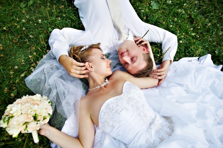 Happy bride and groom on grass in parkの写真素材