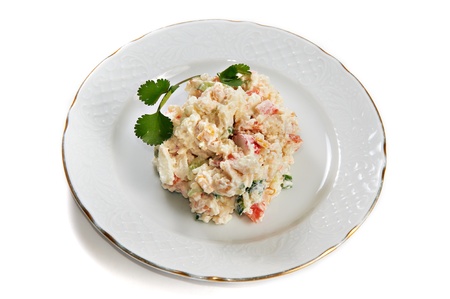 Crab salad of potatoes, crab sticks, corn, eggs and cucumber isolated on plate on white background
の写真素材