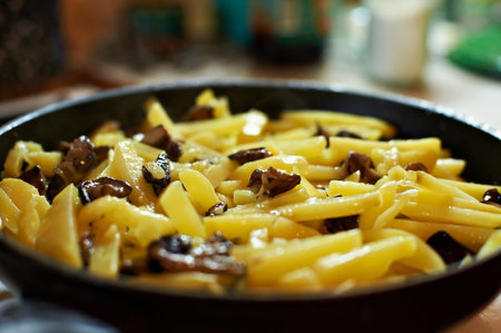 Fried potatoes with mushrooms in a frying pan close-upの写真素材