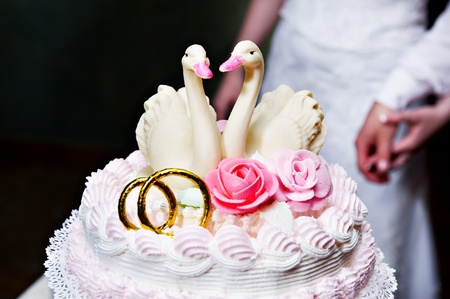 Two swans on a wedding cake and hands of bride and groomの写真素材