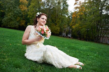 Happy bride in autumn park on wedding walkの写真素材