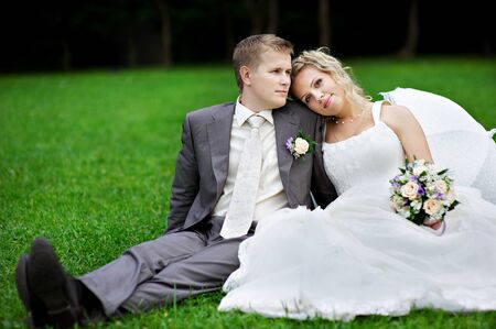 Happy bride and groom on grass in parkの写真素材