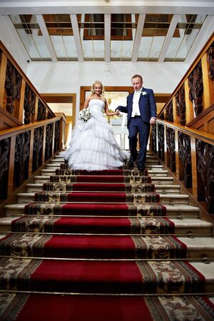 Elegant bride and groom in luxury stairs with red carpet of wedding palaceの写真素材