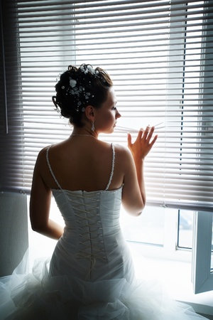 Beautiful bride at the window with the blindsの写真素材