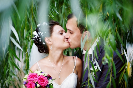 Romantic kiss bride and groom on wedding walkの写真素材