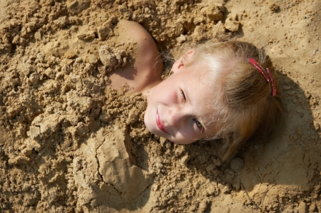 Little girl lying on the sand on the beachの写真素材