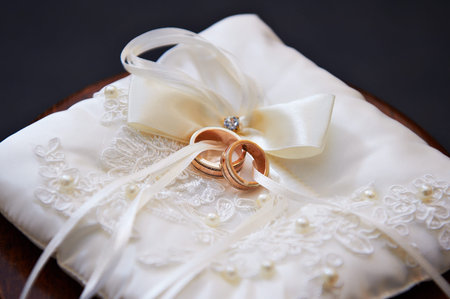 Gold wedding rings on white pillow