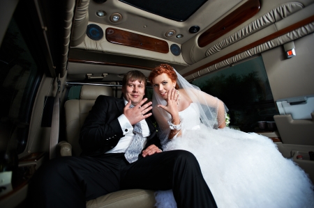 Happy bride and groom into wedding limousineの写真素材