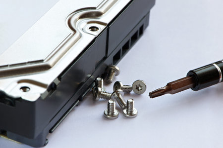Screwdriver and screws near hard drive on white tableの写真素材