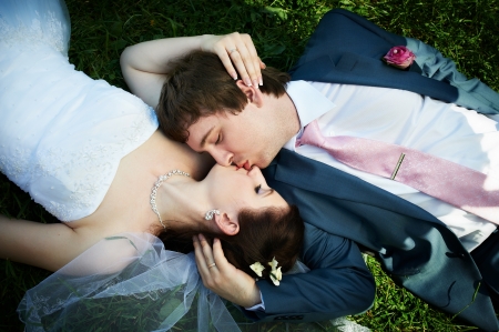 Romantic kiss bride and groom lying on grassの写真素材