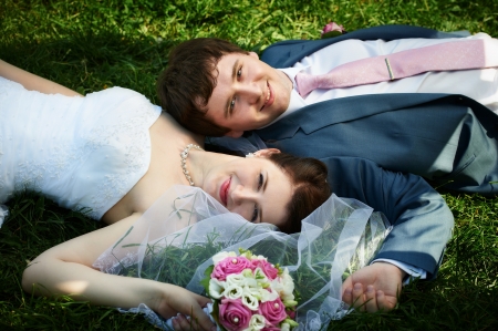 Happy bride and groom at wedding walk on grass in parkの写真素材