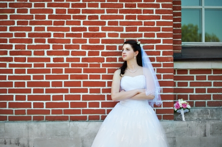 Bride in wedding walk near red brick houseの写真素材
