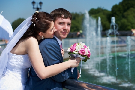 Happy bride and groom with bouquet at wedding walk in the parkの写真素材