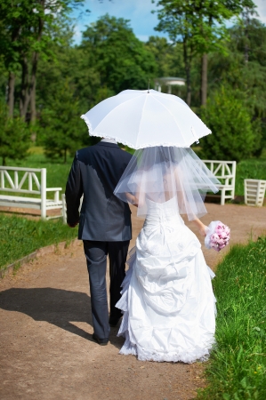 Happy bride and groom goes along the path on wedding walkの写真素材