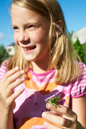 Girl with a grasshopper on a handの写真素材