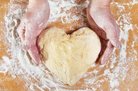 Woman holding dough heart in his handsの写真素材