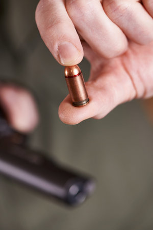 Pistol cartridge in hand shooter on green background