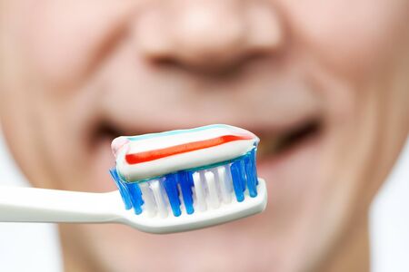 Man brushing teeth toothbrush with toothpaste macro closeupの写真素材