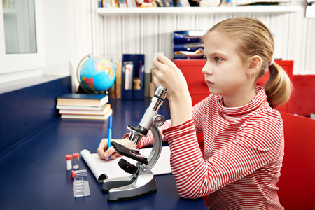 Girl examines drug for the microscope for learning home tableの写真素材