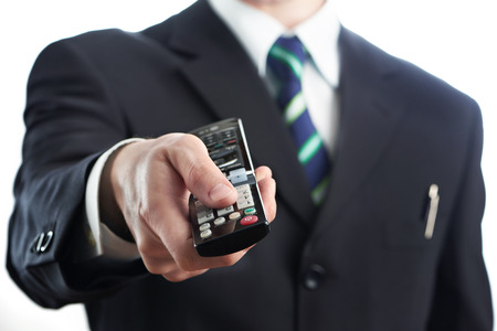 TV remote control in hand of businessman isolated on whiteの写真素材
