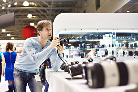 Man photographer tests digital SLR camera in photo exhibitionの写真素材