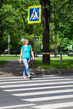 Woman crossing the street at a pedestrian crossingの写真素材