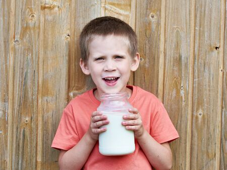 Boy with glass jar of fresh milk near wood wallの写真素材
