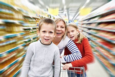 Happy women and children with cart shopping in supermarketの写真素材