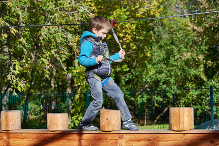 Little boy is climbing to amusement park in sunny day