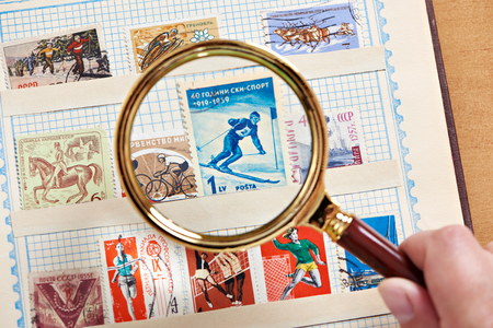 Postage sport stamp with skier under magnifier on album close-upの写真素材