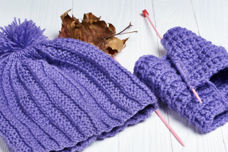 Knitted colorful scarf and hat on white wooden backgroundの写真素材