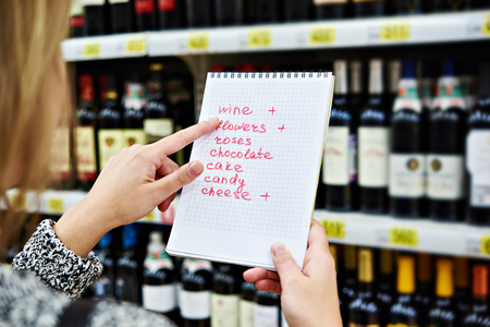 Girl chooses bottle of wine for date in the storeの写真素材