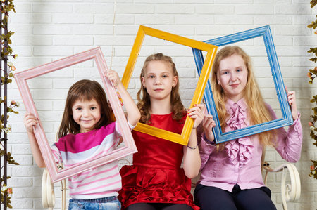 Three girls with frames of paintings posing in the studio
