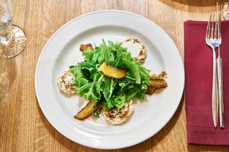 Salad with arugula leaves with fried cheese and orange slices on a dining tableの写真素材