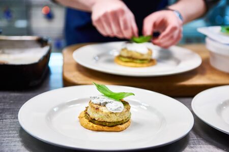 Cook are served at dish with fish cutlet in a restaurantの写真素材