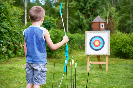 Little boy with big bow near sport aim in sunny summer dayの写真素材